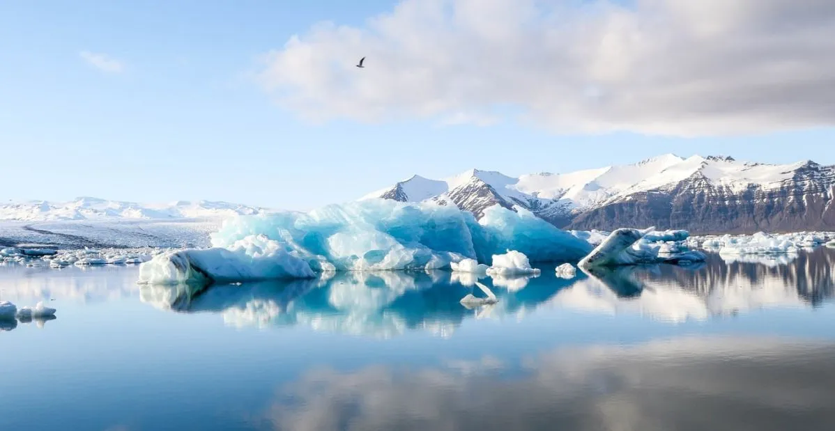 Iceberg azzurri in laguna glaciale con montagne innevate e acqua calma