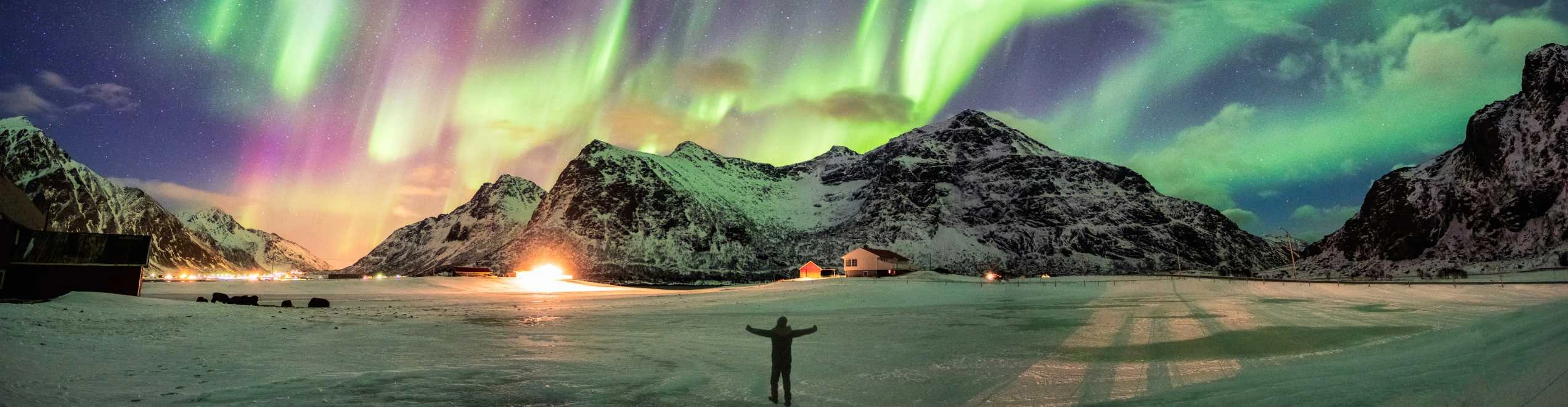 Aurora boreale in Islanda visibile sopra montagne innevate e cielo stellato durante un tour invernale.